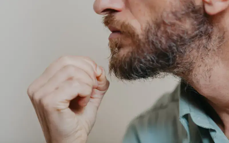 A man pulling out grey beard hair